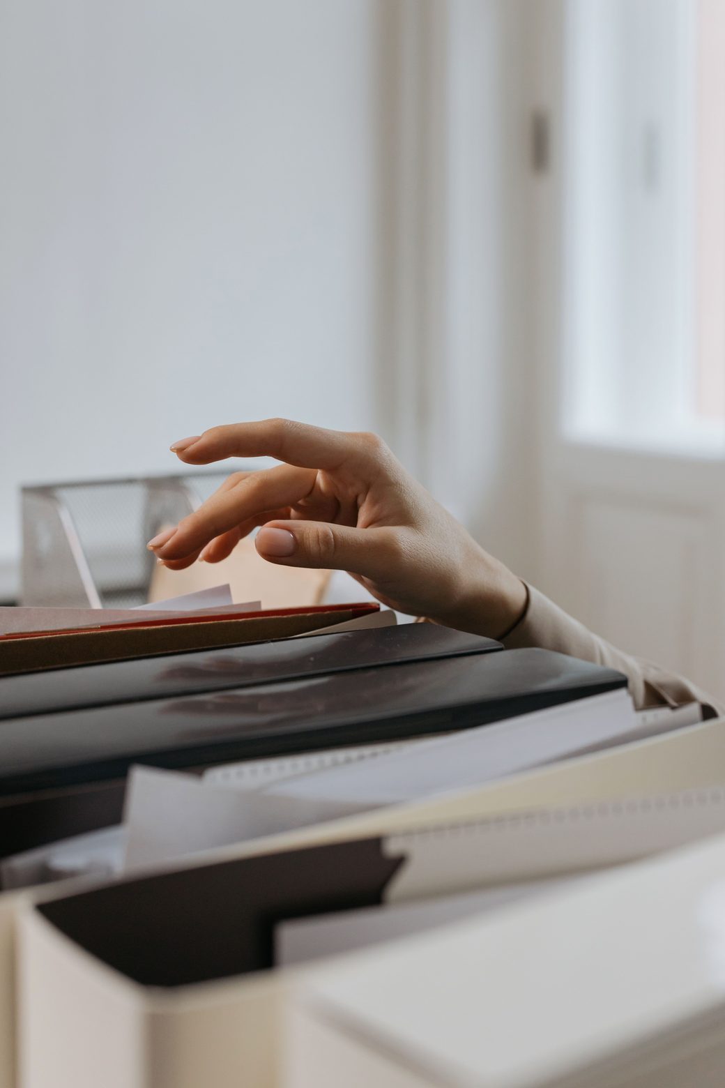 A hand reaching into a drawer of files